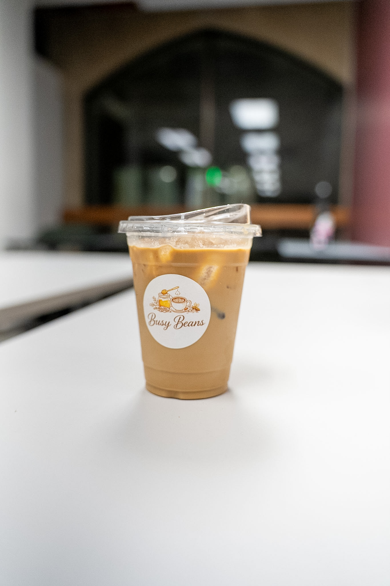 Iced latte in a Busy Beans branded cup