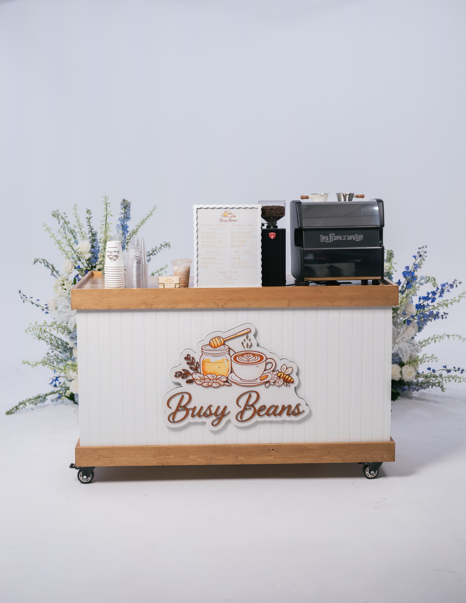 The Busy Beans coffee cart fully set up with La Spaziale espresso machine, custom menu board, and floral arrangement