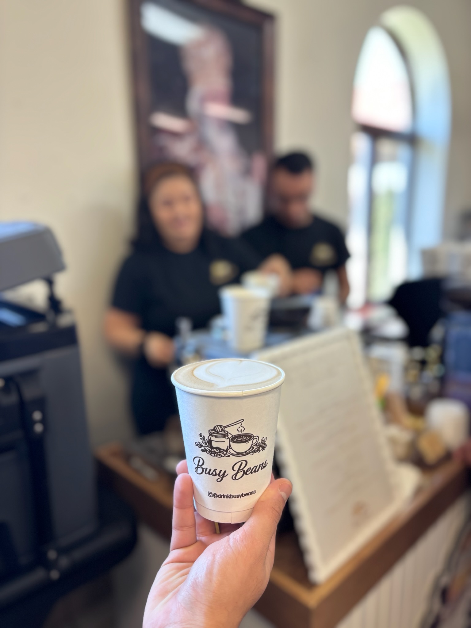 Mark and Kristina with a happy guest holding a Busy Beans cup